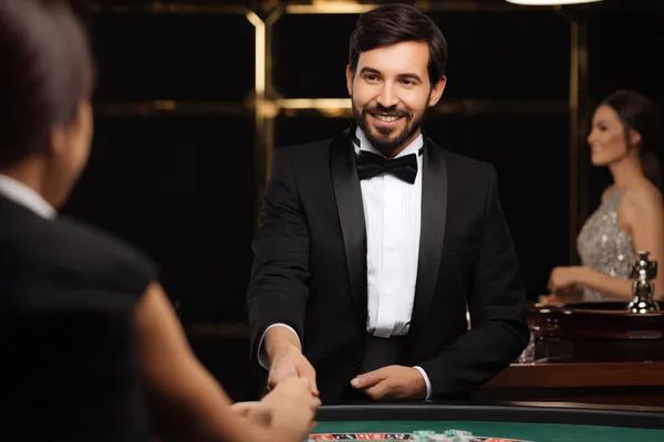 সবুজ বিলাসবহুল গাউন পরা এক নারী অলংকৃত রুলেট চাকার পাশে—যা DC44–এর উচ্চমানের ক্যাসিনো পরিবেশকে প্রকাশ করে।